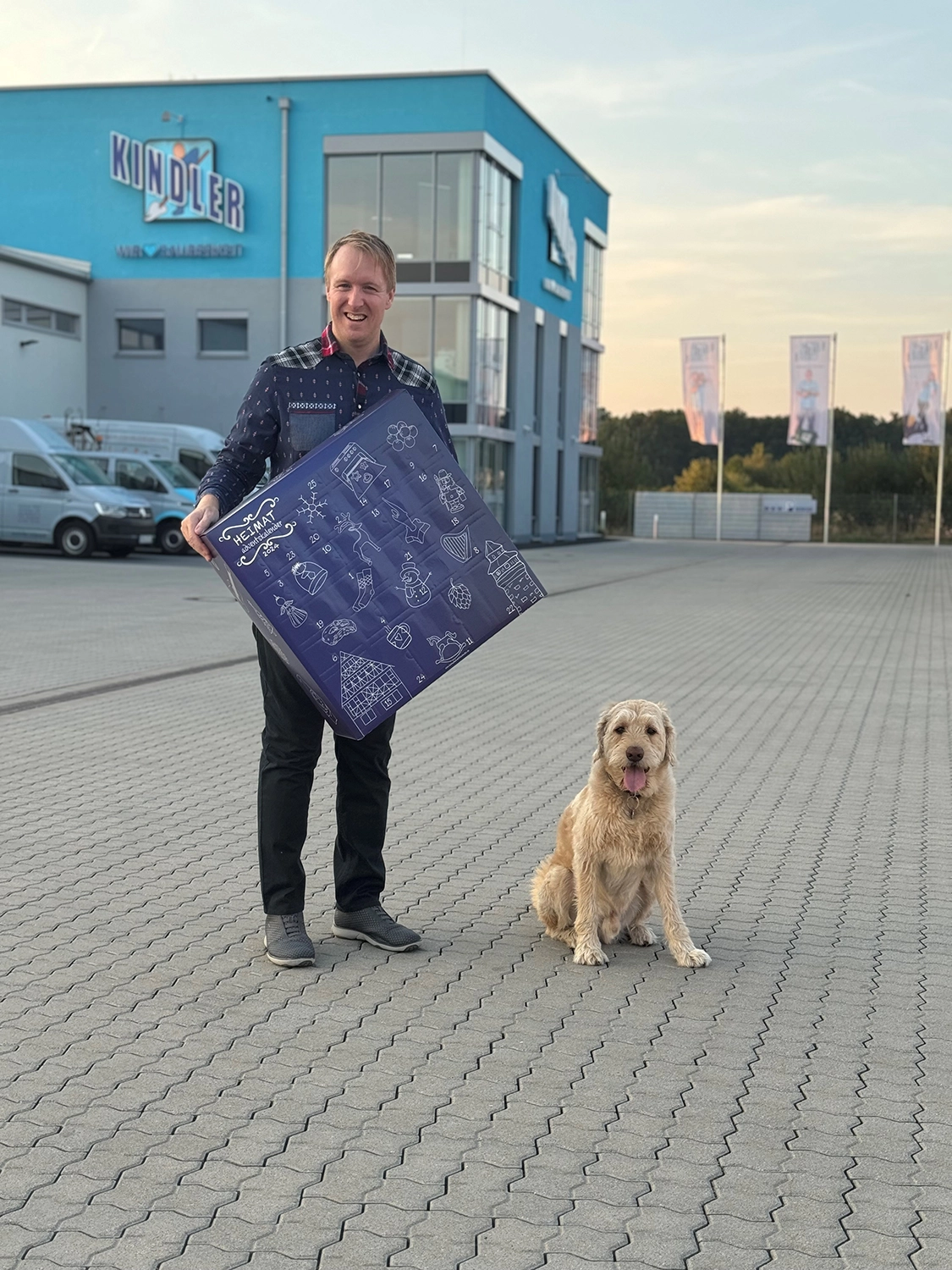 Christian Kindler steht vor der Firma Kinder Gebäudereinigung in Herzogenaurach und hält den HEIMATadventskalender 2024 in der Hand.